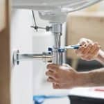 plumber using tools in bathroom
