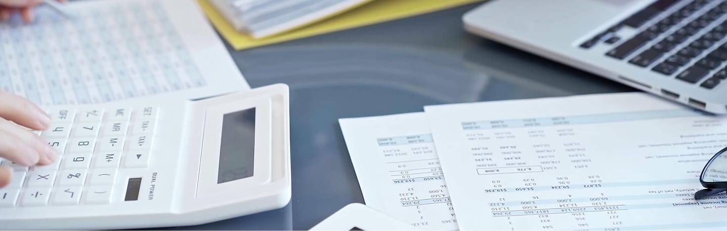 person using calculator and reviewing company report