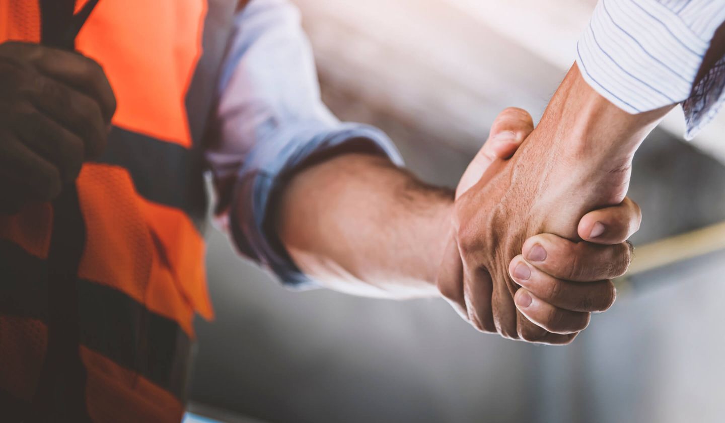 business man and man in construction vest shaking hands